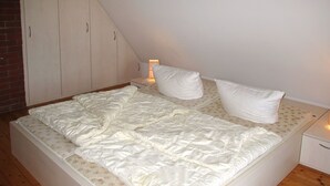 Une chambre avec un lit simple, une table de chevet, une lampe et une armoire.