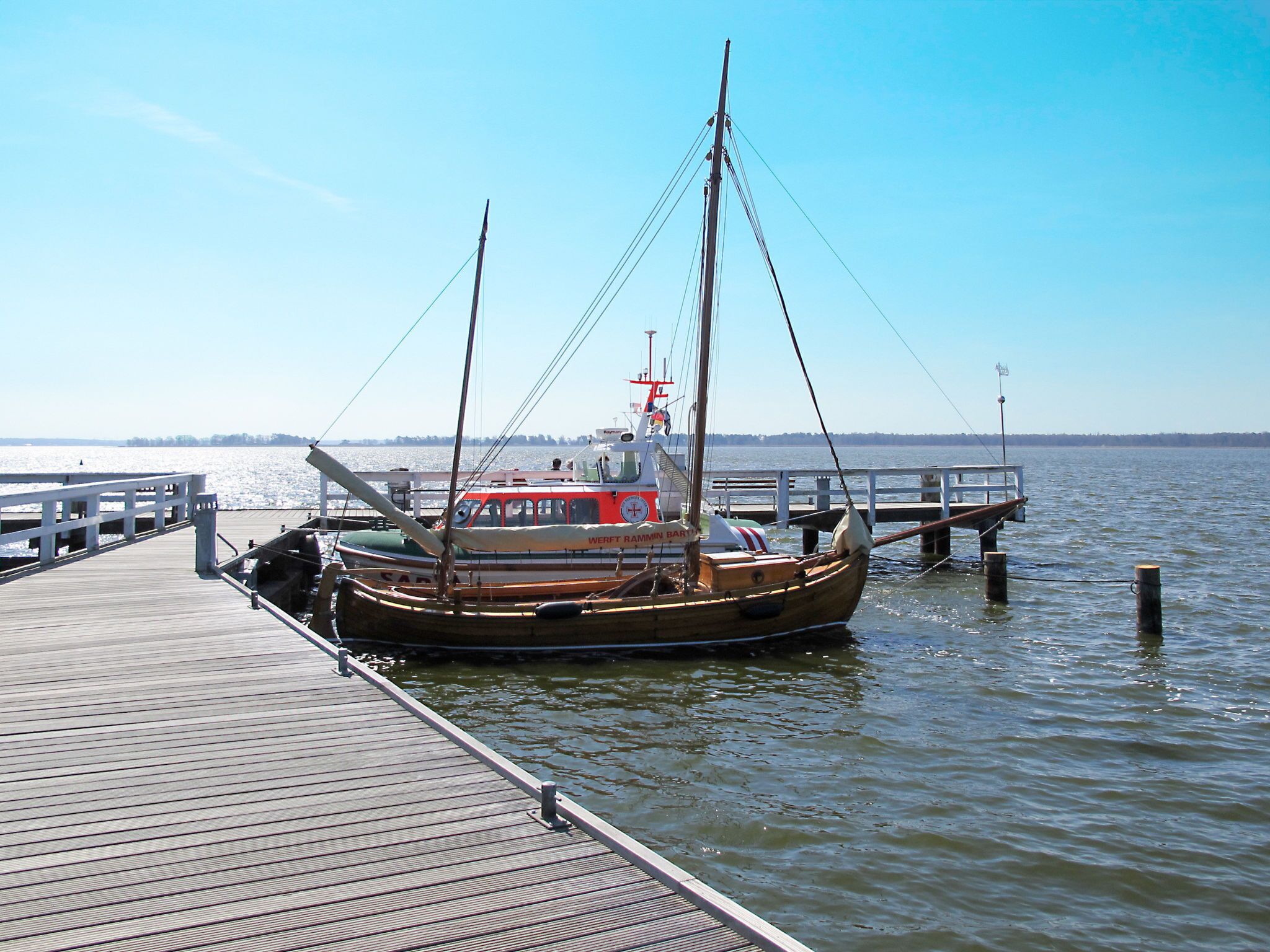 Une jetée en bois s’étendant sur une étendue d’eau calme, avec un bateau amarré à son extrémité.