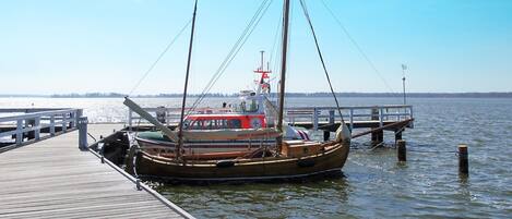 Une jetée en bois s’étendant sur une étendue d’eau calme, avec un bateau amarré à son extrémité.