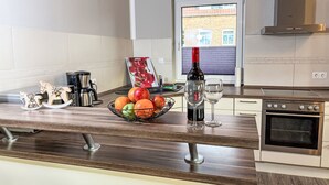 A modern kitchen with a wooden countertop, a wine bottle, a glass, and a fruit bowl. - Johannika by Interhome (Godern)