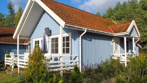 A blue house with a red-tiled roof, white trim, and a porch with white railings. - Wald und See by Interhome (Userin)