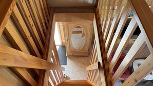 A wooden staircase with a handrail, leading to a landing with a circular window. - Wald und See by Interhome (Userin)