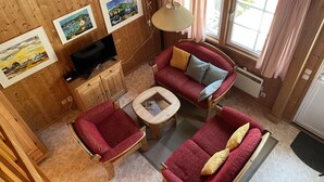 A cozy room with wooden walls, a red sofa set, a television, and framed artwork on the wall. - Wald und See by Interhome (Userin)