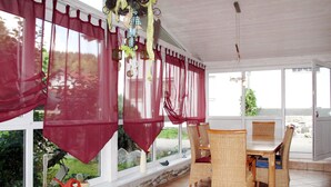 Un patio cubierto con muebles de mimbre, una pared de piedra y vistas al exterior.