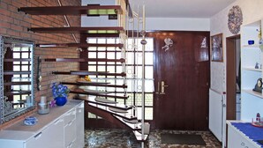 Une cuisine avec un mur en briques, un escalier en bois et une porte ornée d’un ange.