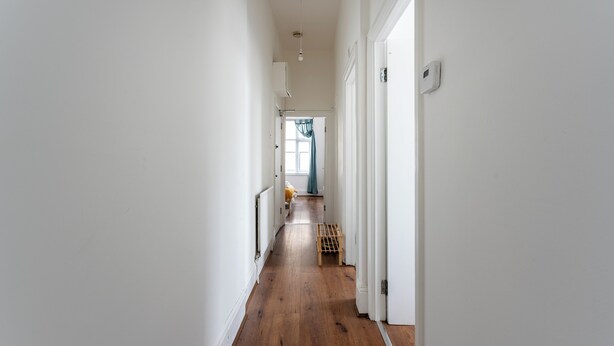 Un couloir étroit avec un plancher en bois et des murs blancs.