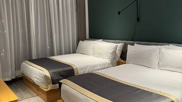 A hotel room with two beds, a desk, a chair, and a large window with curtains.