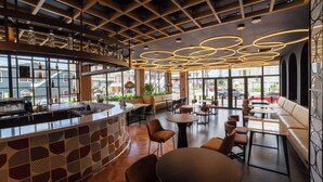 Een modern café met een bar, zitplaatsen en grote ramen.