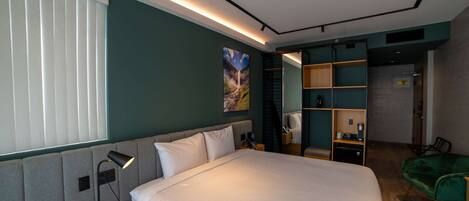 Una habitación de hotel moderna con una cama grande, un escritorio, una silla y estanterías empotradas.