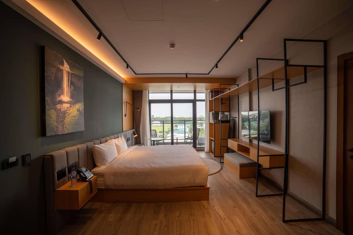 Ein modernes Hotelzimmer mit einem großen Bett, einem Fernseher und einem Balkon mit Blick.