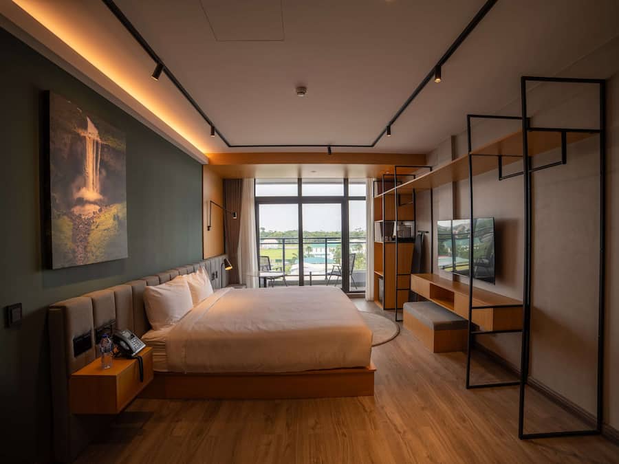 Ein modernes Hotelzimmer mit einem großen Bett, einem Fernseher und einem Balkon mit Blick.