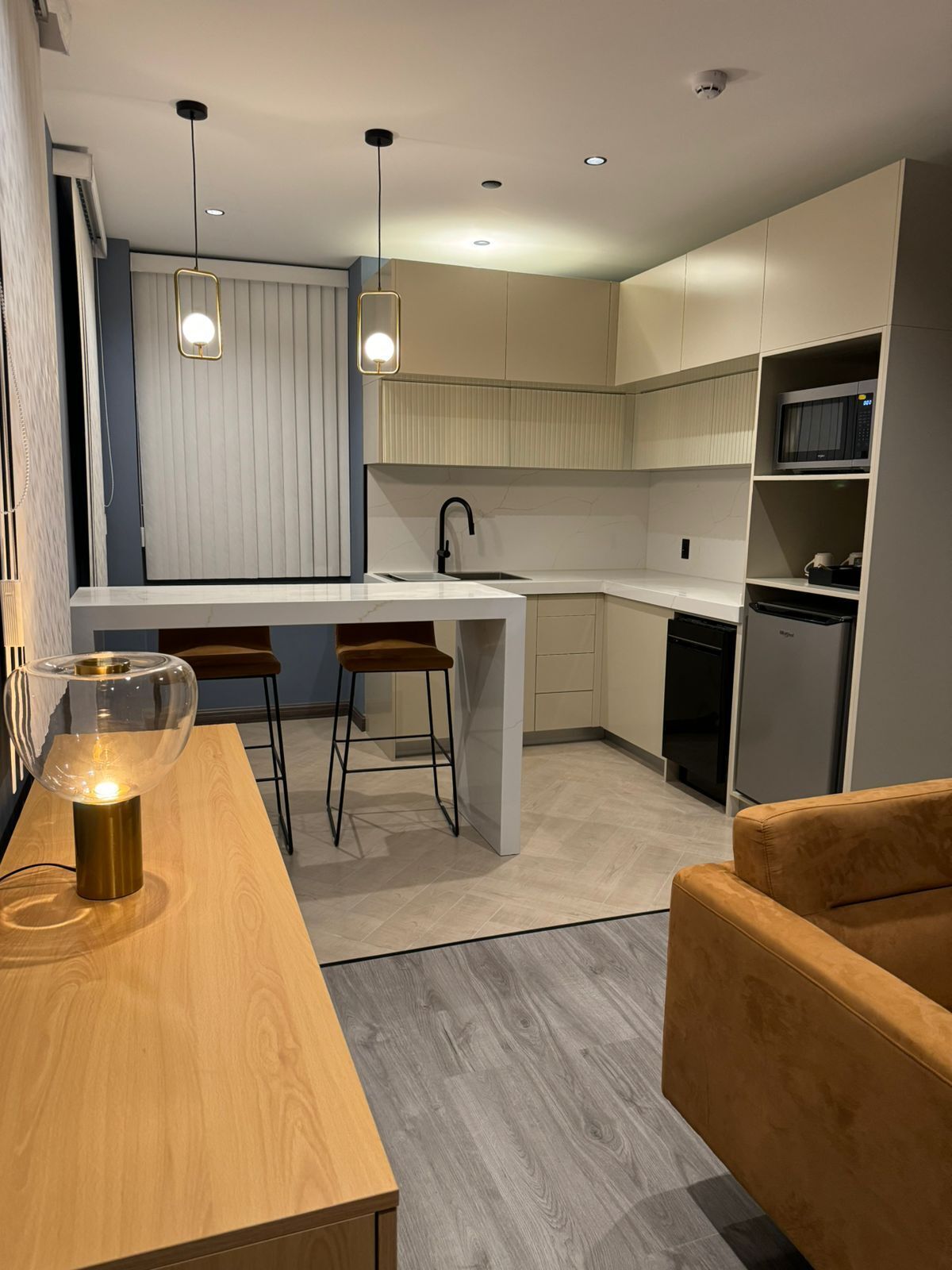 Une cuisine moderne dotée d’un îlot central, de luminaires suspendus et d’un four à micro-ondes.
