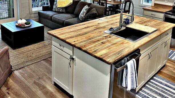 A modern kitchen with a wooden countertop, a built-in sink, and a dining area with a table and chairs.