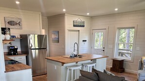 A modern kitchen with a stainless steel refrigerator, wooden countertops, and a central island with stools.