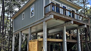 A two-story house with a balcony, a covered porch, and a wooden deck.