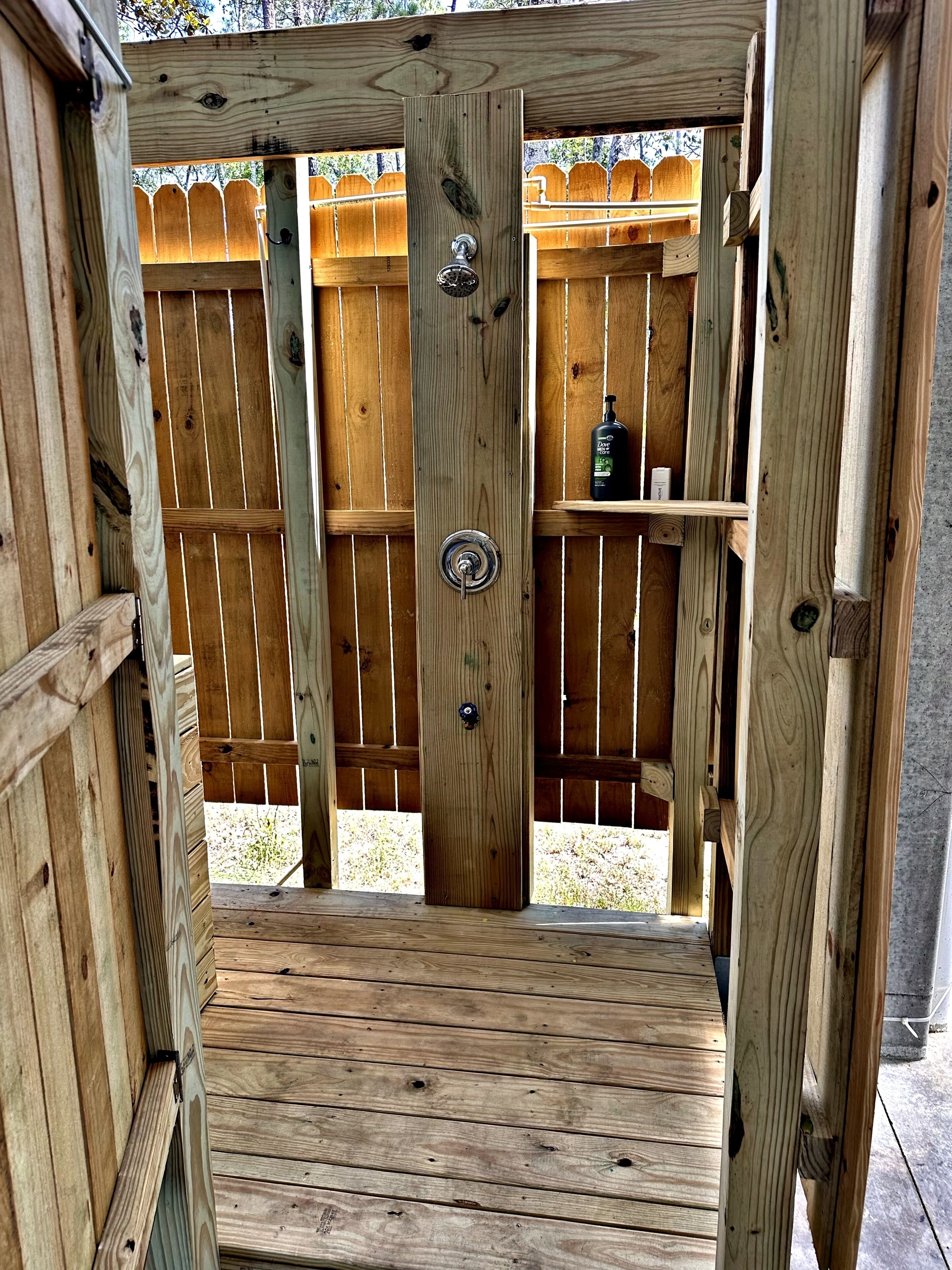 A wooden structure with a metal door and a shelf with a bottle.