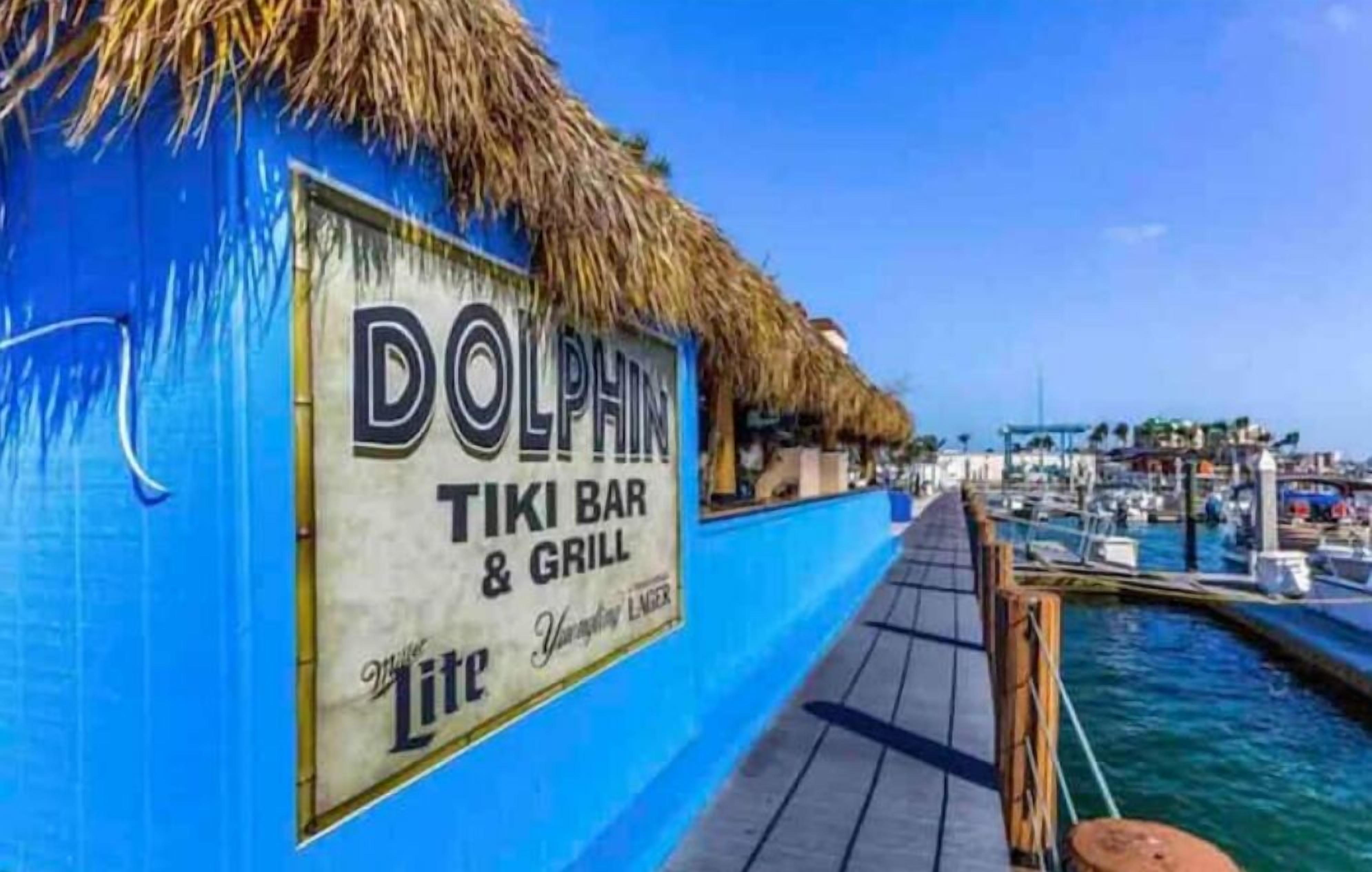 A Dolphin Tiki Bar & Grill with a thatched roof and a view of the marina.