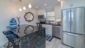 A modern kitchen with a marble island, stainless steel appliances, and pendant lighting. - Beautiful modern gulf coast condo  Marco Island, FL (Marco Island)