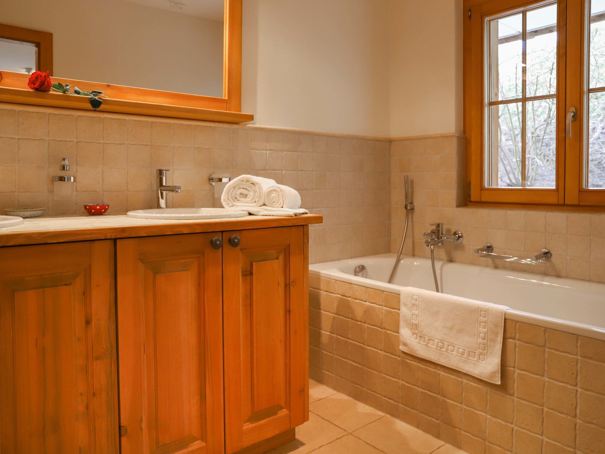 Une salle de bain avec des meubles en bois, un lavabo, une baignoire et une fenêtre.