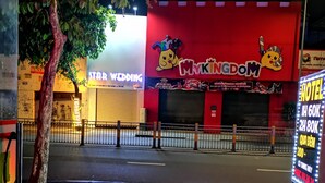 A street view at night with a brightly lit building featuring a 'My Kingdom' sign, a 'Star Wedding' sign, and a 'Hotel' sign with pricing information. - Nhu Y Hotel (Ho Chi Minh City)