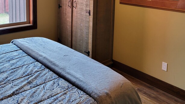 A bedroom with a bed, a wardrobe, a painting, and a window with blinds. - Heron cabin (eureka)