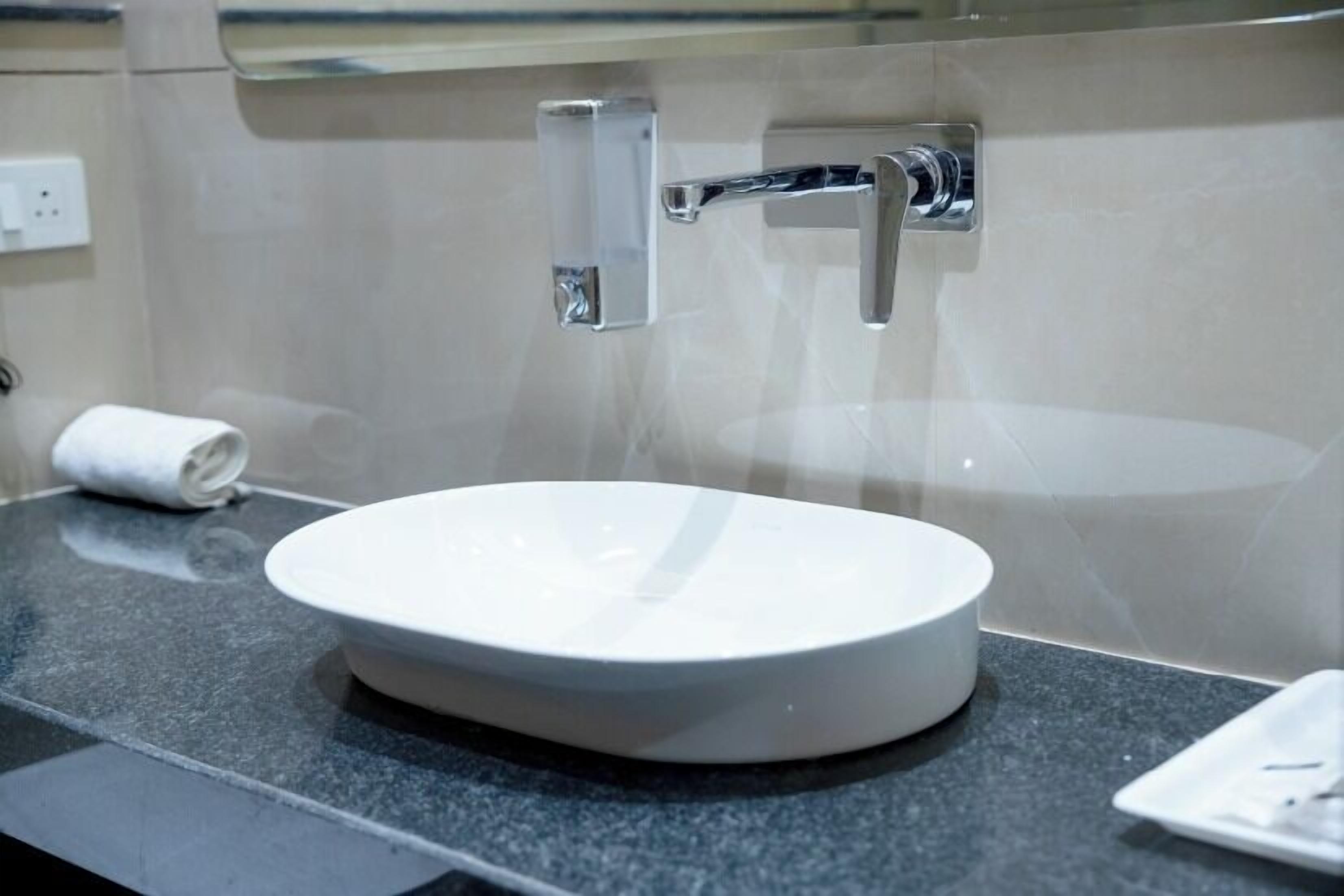 Un baño moderno con un lavabo blanco, grifo cromado y una toalla sobre la encimera.
