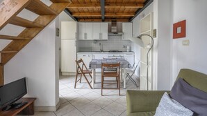 A kitchen with white cabinets, a wooden ceiling, and a dining area with a checkered tablecloth. - Angelico Urban Loft (Florence)