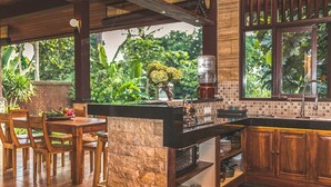 A kitchen with wooden cabinets, a marble countertop, and a window overlooking a lush garden. - Jungle Villa - Two Bedroom Villa, Sleeps 4 (Sayan)