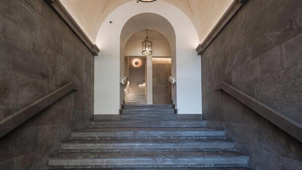 A grand staircase with stone walls and a circular light fixture at the top. - Exquisite 2-Bedroom Luxury Apartment in Piazza della Signoria (Firenze)