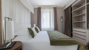 A hotel room with a bed, bedside table, lamp, and a large closet. - Exquisite 2-Bedroom Luxury Apartment in Piazza della Signoria (Firenze)