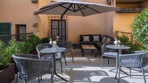 An outdoor seating area with wicker chairs and tables, a large umbrella, and a sofa. - Exquisite 2-Bedroom Luxury Apartment in Piazza della Signoria (Firenze)