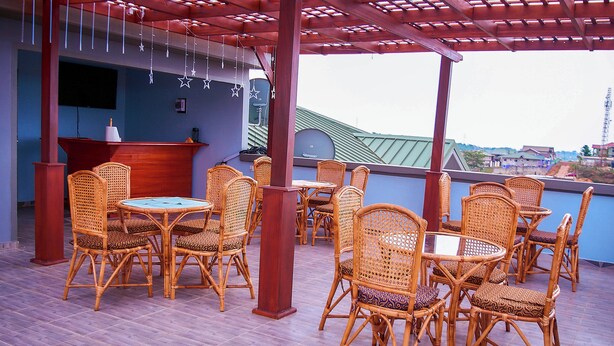 A covered outdoor seating area with wicker furniture and a bar counter. - Thy Favour Hotel (Sekondi-Takoradi)