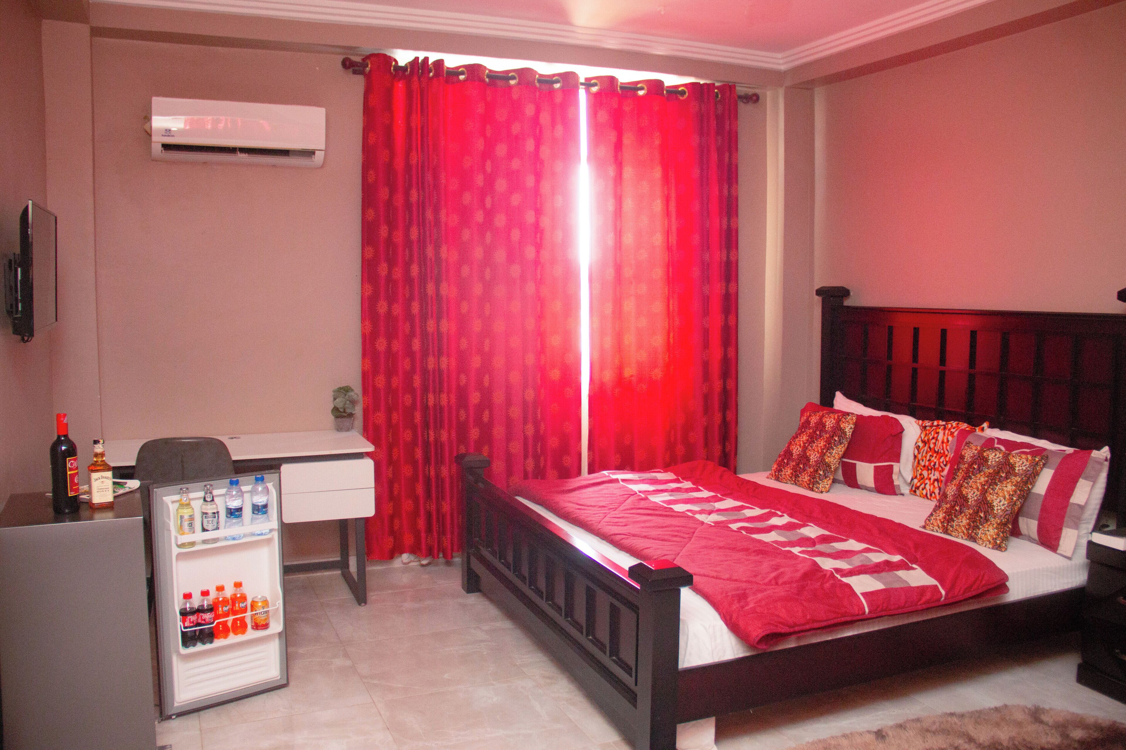 A bedroom with a bed, a desk, and a mini-fridge.