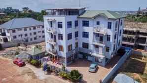 A multi-story building with balconies, a parking area, and a construction site nearby. - Thy Favour Hotel (Sekondi-Takoradi)