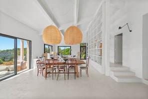 A modern dining area with a large table and chairs, two hanging rattan lamps, and a view of greenery outside. - Air-conditioned villa, superb sea and island views, 4 bedrooms, small pool (Hyères)