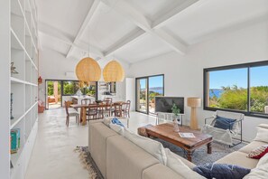 A spacious living area with a large window, a dining table, and a sofa. - Air-conditioned villa, superb sea and island views, 4 bedrooms, small pool (Hyères)