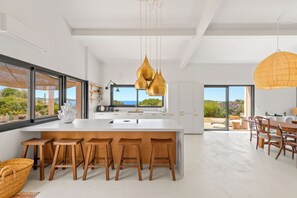 A modern kitchen with a central island, bar stools, and pendant lighting. - Air-conditioned villa, superb sea and island views, 4 bedrooms, small pool (Hyères)