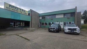 Ett motell med en skylt som visar texten ”Motell, restaurang, pub och bar”. Två bilar står parkerade framför.