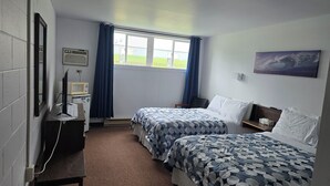 Una habitación con dos camas, un escritorio con computadora, una silla, una ventana con cortinas y un cuadro en la pared.