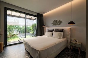 A modern hotel room with a large bed, a nightstand, a digital clock, and a view of the outdoors.