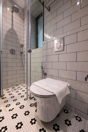 A bathroom with a shower, toilet, and patterned floor tiles.