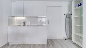 Cocina compacta con muebles blancos, horno empotrado y una pequeña encimera.