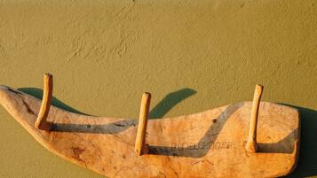 A wooden boat-shaped object with three hooks on a textured surface.