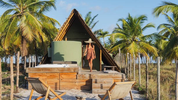 A wooden beach hut with a thatched roof, surrounded by palm trees. - Cabanas Blue (Mata de São João)