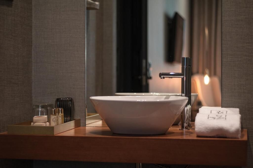 A modern bathroom with a large white sink, a mirror, and a wooden vanity.