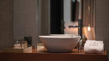 A modern bathroom with a large white sink, a mirror, and a wooden vanity.