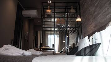 Une chambre d’hôtel avec un grand lit, un bureau et un miroir. Il y a un climatiseur fixé au mur et un luminaire suspendu au plafond.