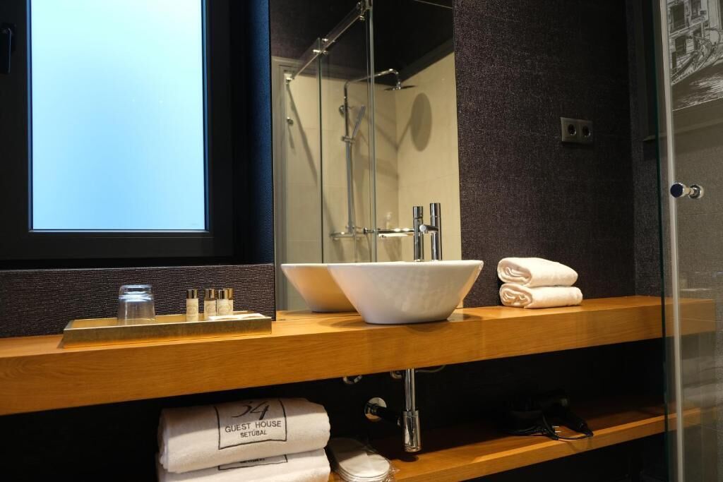 Un baño moderno con un espejo grande, un lavamanos blanco y una cabina de ducha de cristal.