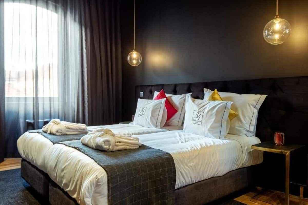 Una habitación de hotel con una cama grande, dos mesitas de noche y un ventanal con cortinas.