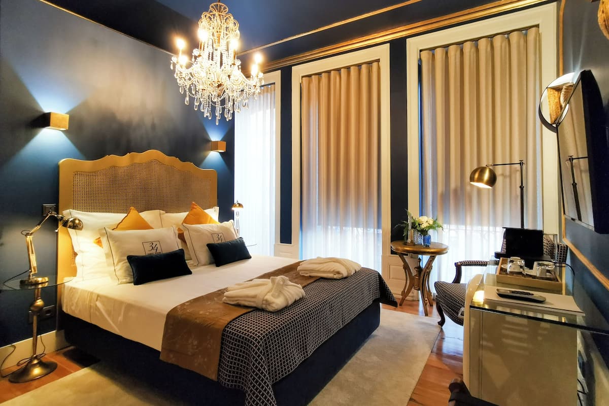 Una habitación de hotel con una cama grande, un candelabro, un escritorio con lámpara y un televisor.